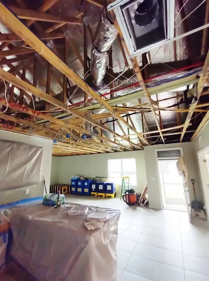 An opened ceiling with containment plastic and drying equipment set up beneath it