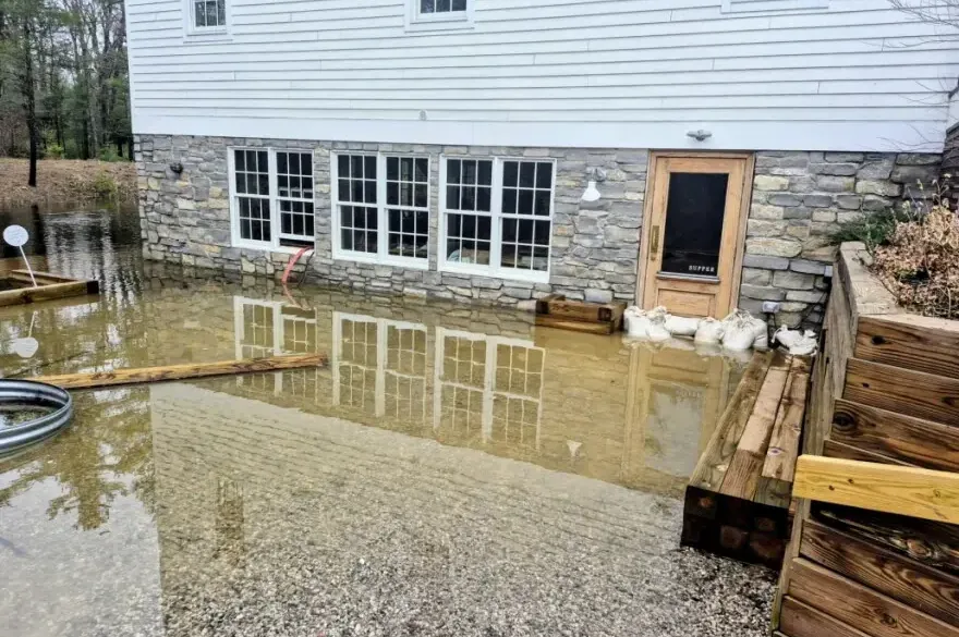 Storm water pooled against a walkout wall with sandbags stacked at the door
