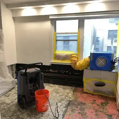 A dehumidifier and an air mover drying a room where the flooring has been removed