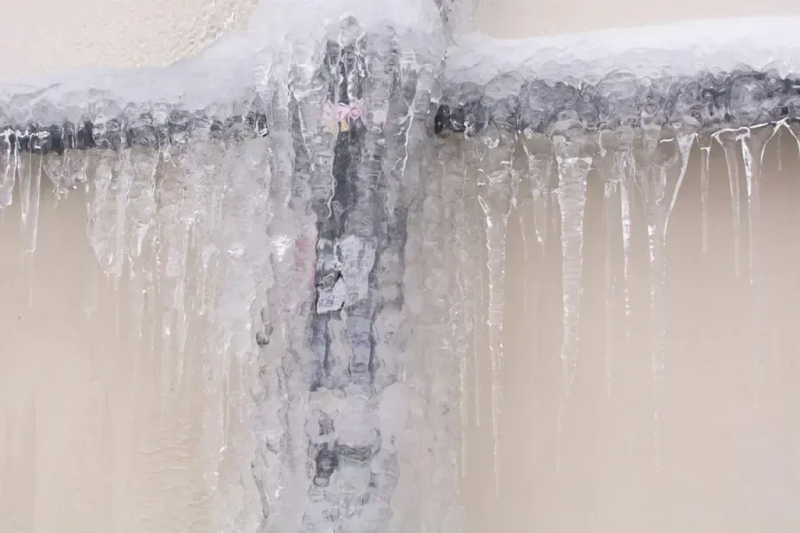 Ice coating a frozen pipe that has split open inside a home